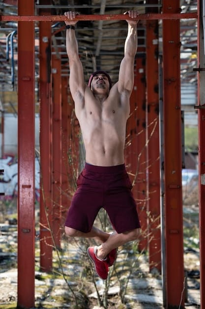 A person performing towel pull-ups, with two towels draped over a pull-up bar, demonstrating an extreme grip challenge.