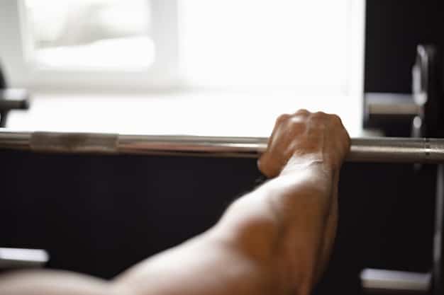 A close-up shot of a weightlifter's hands gripping a barbell tightly during a bench press, illustrating proper hand placement and focus.