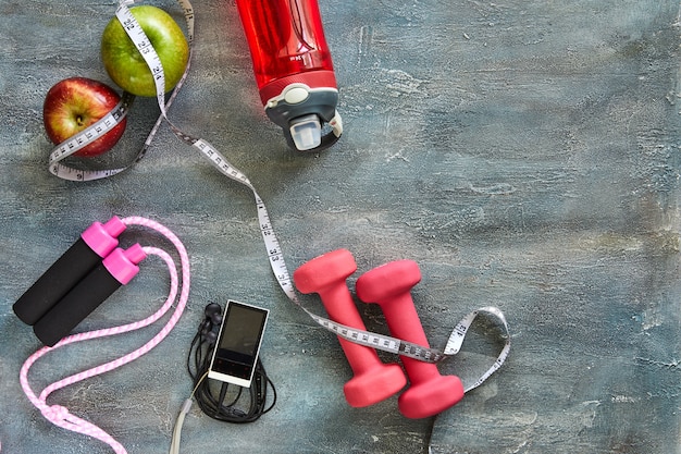 A detailed flat lay of essential home gym equipment including dumbbells, resistance bands, a jump rope, and a yoga mat, set up for a circuit training session.