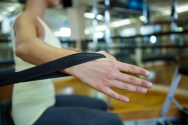A person's hands gripping a thick resistance band, pulling it apart to demonstrate hand and wrist extension exercises in a gym setting.