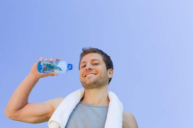 A person holding a glass of water with ice, looking refreshed after a workout. In the background, there's a vibrant array of colorful fruits and vegetables, emphasizing the importance of hydration and micronutrients.