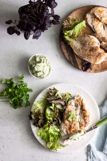 A close-up of a diverse meal prep set, featuring grilled chicken, leafy green salad, avocado, and a small portion of berries, illustrating a balanced ketogenic meal.